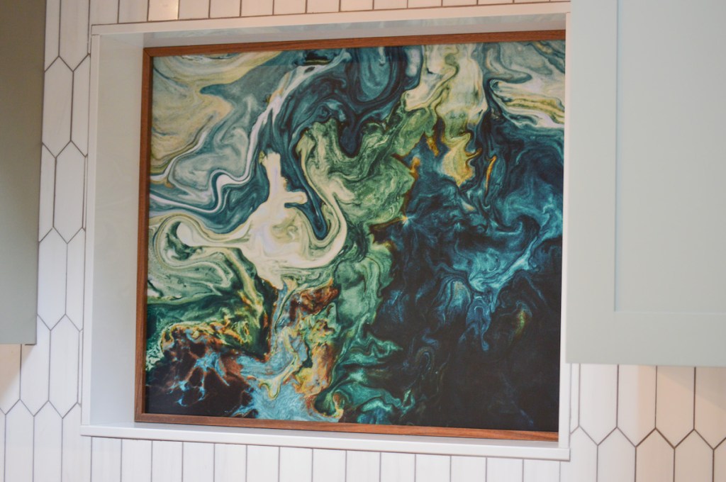 Close up of custom aluminum artwork in framed niche in white kitchen wall